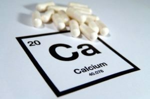 Eine Handvoll Pillen auf dem Hintergrund der chemischen Bezeichnung von Kalzium